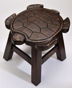 a small wooden stool with carved designs on the top and bottom, sitting against a white background