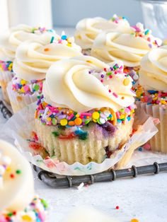 cupcakes with white frosting and sprinkles on a cooling rack