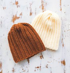 two knitted beanies sitting on top of a wooden table next to each other