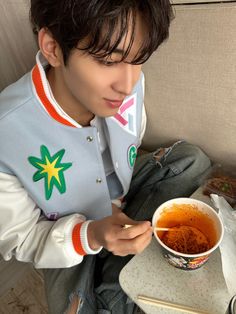 a man sitting on a couch holding a bowl of food in his hand and looking down