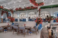 the restaurant is decorated with red flowers and greenery on the ceiling, along with blue chairs