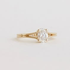 a yellow gold engagement ring with an oval cut diamond in the center, on a white background