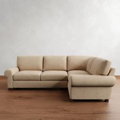 a beige couch sitting on top of a hard wood floor next to a white wall