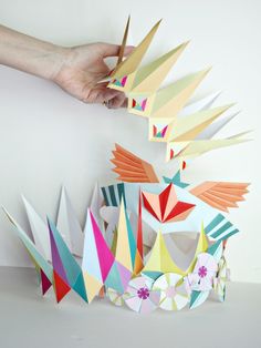 a hand is holding scissors over an origami bird