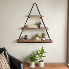 three shelves with plants and books on them in the corner of a living room, along with a black leather chair