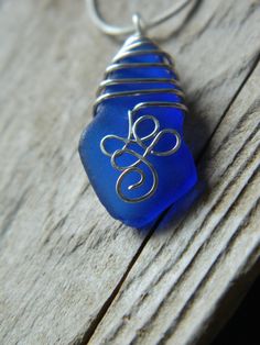 a blue glass bead is sitting on a piece of wood with a silver wire