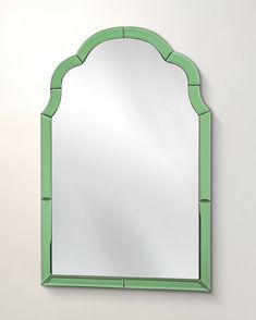 a mirror that is on the wall with a green border around it and an arch shaped frame