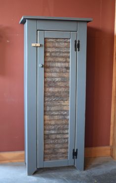 a tall gray cabinet sitting next to a red wall