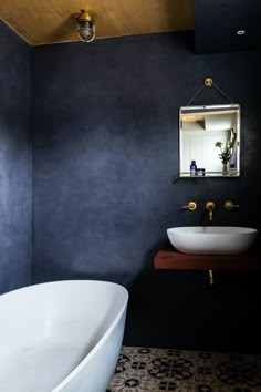 a white bath tub sitting next to a sink in a bathroom under a wooden ceiling