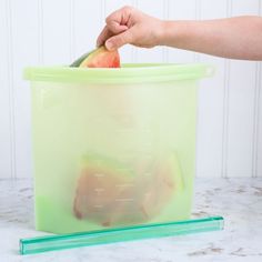 a person holding an apple in a plastic container