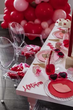 a table set for valentine's day with pink and red balloons