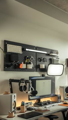 a desk with a computer and speakers on it in front of a wall mounted speaker system