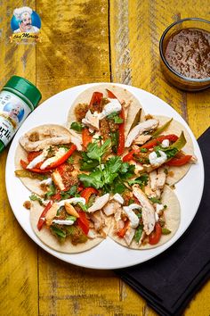 a white plate topped with tacos covered in meat and veggies