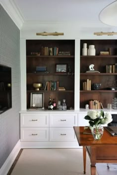 a living room filled with lots of bookshelves next to a desk and chair