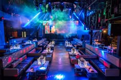 an empty restaurant is lit up with colorful lights and blue lighting on the walls, along with couches and tables