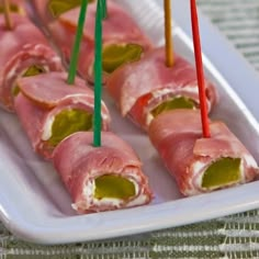 several pieces of ham wrapped in green sauce and toothpicks on a white plate