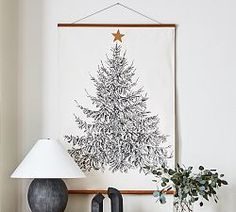 a christmas tree is hanging on the wall above a table with two lamps and a vase