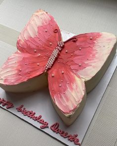 a cake shaped like a pink butterfly with pearls on it's wings and the words happy birthday written in red