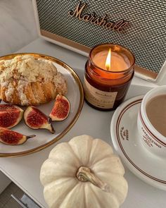 a table topped with a plate of food next to a cup of coffee and a candle