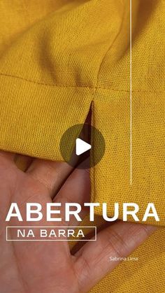 a person is holding their hand near the pocket of a yellow shirt that says abertura na barra