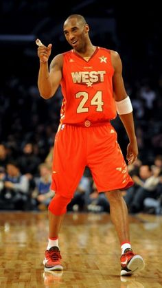 a basketball player in an orange uniform on the court with his hand up and smiling