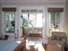 a living room filled with furniture and lots of windows next to a bed in a bedroom