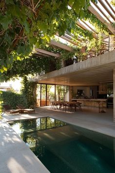 an outdoor swimming pool surrounded by trees and greenery next to a house with large windows