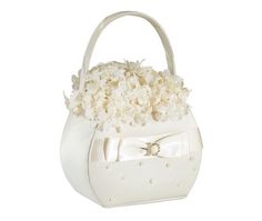 a white purse with flowers on the front and bow at the bottom, sitting on a white surface