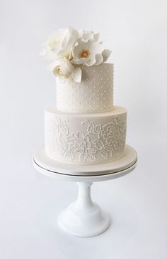 a three tiered cake with white flowers on top