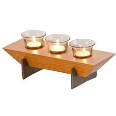 three tealight candles are placed on a wooden stand with two glass bowls in the middle