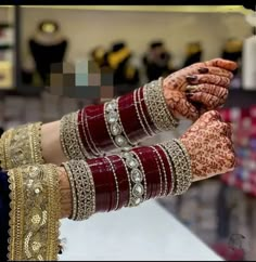 two hands holding each other with bracelets and rings on their wrists, in front of a store display