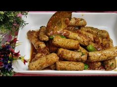 a white plate topped with fried food next to flowers