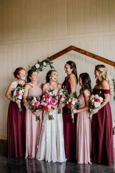 a group of women standing next to each other in front of a wall with flowers