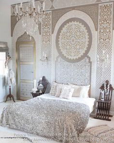 a bedroom decorated in white and silver with an intricate wallpaper pattern on the walls