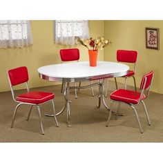 a white table with four red chairs and a vase full of flowers on the side