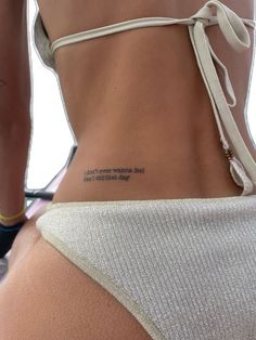 the back of a woman's body with tattoos on her left side and words written in black ink