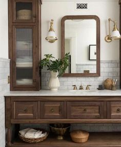 a bathroom with a large mirror, sink and wooden cabinet in the middle of it