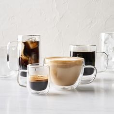 there are many different types of cups on the table with one cup full of coffee