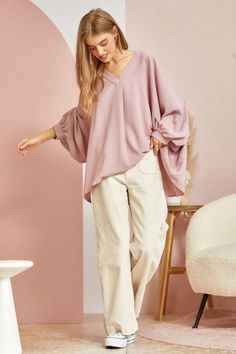 This blouse is out to prove that comfy and chic can coexist in perfect harmony. Its flowy, dolman cut gives you room to breathe while still maintaining a flattering drape. 3/4 sleeves keep it seasonal, transitioning effortlessly from summer to fall. A plunging V-neckline shows just enough skin to be subtly seductive, but the blush pink hue is as sweet and charming as an English rose garden. In short, this top lets you make a stylish statement without having to sacrifice one ounce of comfort. It’ Effortless V-neck Blouse For Fall, Effortless Fall V-neck Blouse, Feminine Rayon Tops For Fall, Chic Flowy Top With Lantern Sleeves, Oversized Versatile V-neck Blouse, Versatile Oversized V-neck Blouse, Fall Feminine Rayon Tops, Casual Oversized Blouson Sleeve Blouse, Effortless Rayon Blouse For Spring