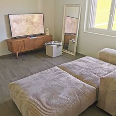 a living room with two beds and a flat screen tv on the wall above it