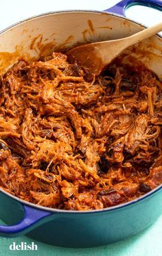 a blue pot filled with shredded meat on top of a table