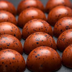 many brown eggs with black speckles sitting on top of each other in rows