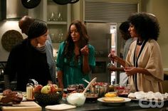 three women standing around a kitchen counter with food on it and one woman holding a knife