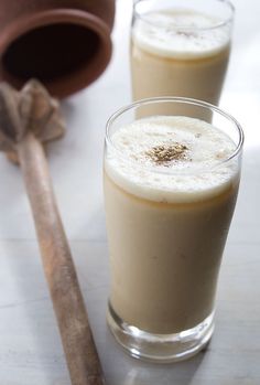 two glasses filled with liquid next to cinnamon sticks