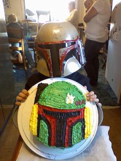 a cake that looks like the boba fett helmet is being held by someone