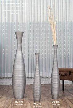 three tall vases sitting on top of a wooden floor