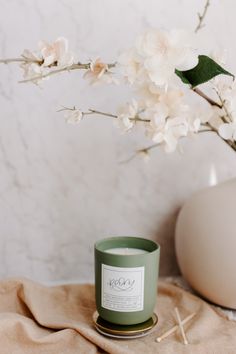 a green candle sitting on top of a table next to flowers