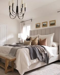 a bedroom with a bed, chandelier and pictures on the wall above it