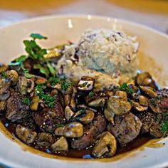 a white plate topped with meat and mushrooms