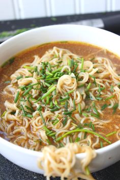 a white bowl filled with noodles and green onions